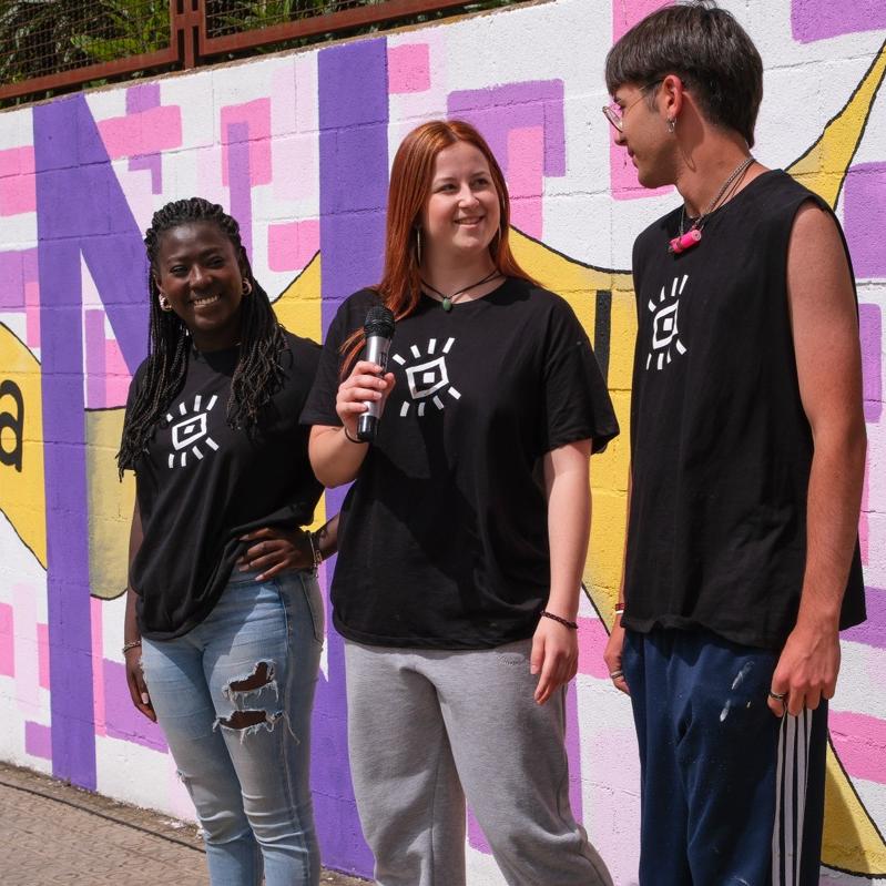 Tres persones davant la paret amb el mural