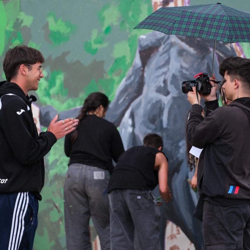 Persones gravant davant el mural